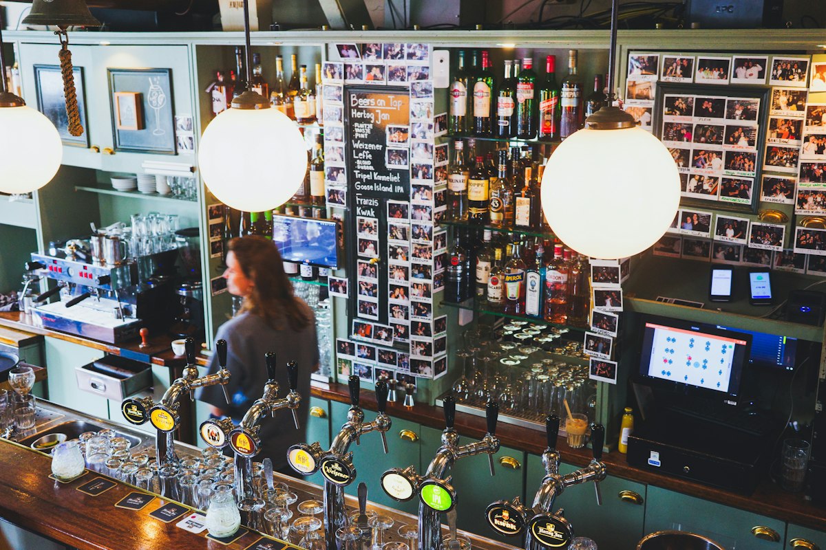 Bartender working behind a bar with beer taps (illustrative photo)