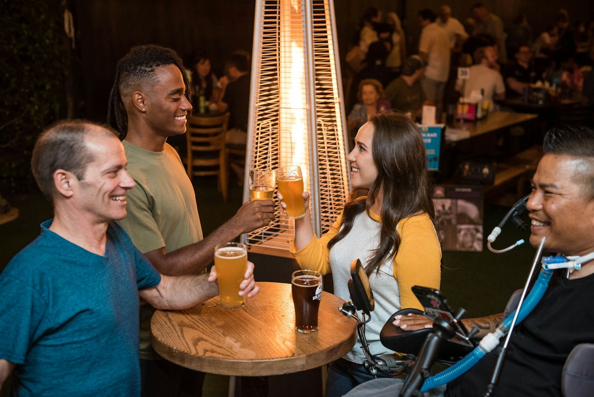 Friends holding beer glasses at a bar (illustrative photo)